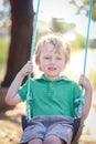 Little blonde boy playing on swing at preschool for kindy portraits Royalty Free Stock Photo