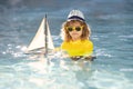 Little blonde boy put toy boat in the sea waves at the beach during summer vacation. Summer with kids vacation. Dream on Royalty Free Stock Photo