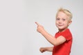 Little blonde boy in red t-shirt points his finger. Space for text. Place for advertising. White background Royalty Free Stock Photo