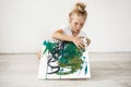 Little blonde female child with hairbn and freckles wearing white t-shirt occupied with her picture. Cute, adorable girl