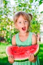 Little blonde girl with big slice watermelon in summer time in park, outdoor. Surprise child. Oops, wow