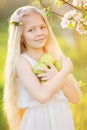 Little blonde girl in blossom garden with apples Royalty Free Stock Photo