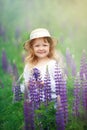 Little blonde girl with curly hair walking in a field with lupins, blowing soap bubbles, summer evening Royalty Free Stock Photo