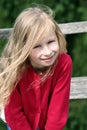 little blonde girl with curly long hair, portrait, in a red sweater in the sun Royalty Free Stock Photo