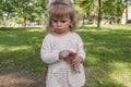 Little blonde girl in a cute dress holding aspen mushroom in her hand Picking edible mushrooms on the green lawn in the park. Royalty Free Stock Photo