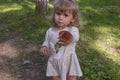 Little blonde girl in a cute dress holding aspen mushroom in her hand Picking edible mushrooms on the green lawn in the park. Royalty Free Stock Photo