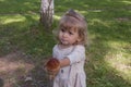 Little blonde girl in a cute dress holding aspen mushroom in her hand Picking edible mushrooms on the green lawn in the park. Royalty Free Stock Photo