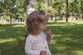 Little blonde girl in a cute dress holding aspen mushroom in her hand and smelling it. Picking edible mushrooms on the green lawn Royalty Free Stock Photo