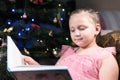 A little blonde girl in a festive dress with a book in her hands sits next to soft toys against the background of a Royalty Free Stock Photo