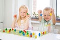 little blonde girl hold red people figure in hand. yellow, blue, green wood chips in children play - Board game and kids leisure c