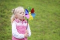 Little blonde girl holding multicolored pinwheel in her ha