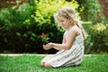 Little blonde girl holding young flower plant in hands on green background Royalty Free Stock Photo