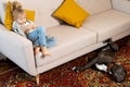 a little blonde girl at home on the sofa with a mobile phone and a big dog, children and gadgets