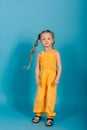 Little blonde girl, she laughing, sitting on floor, posing isolated on blue. Childhood, fashion Royalty Free Stock Photo