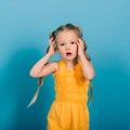 Little blonde girl, she laughing, sitting on floor, posing isolated on blue. Childhood, fashion Royalty Free Stock Photo