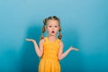 Little blonde girl, she laughing, sitting on floor, posing isolated on blue. Childhood, fashion Royalty Free Stock Photo