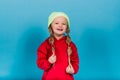 Little blonde girl, she laughing, sitting on floor, posing isolated on blue. Childhood, fashion Royalty Free Stock Photo