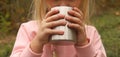 Little blonde girl in light pink sweatshirt drinking hot tea from stainless steel cup. Autumn picnic, camping, travel, trekking. Royalty Free Stock Photo