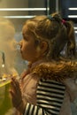 A little blonde girl looks at a glass shop window. Royalty Free Stock Photo