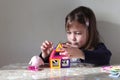 A little blonde girl with loose blonde hair is building a toy house Royalty Free Stock Photo