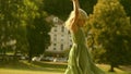 Little blonde girl performs handspring on a green park lawn on a sunny summer day