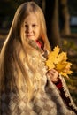 little blonde girl in a plaid whip in the park in autumn Royalty Free Stock Photo