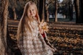 Little blonde girl in a plaid whip in the park in autumn Royalty Free Stock Photo