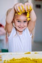 Little blonde girl play with yellow magic sand on white glowing table. Sensory development. Lessons in kindergarten Royalty Free Stock Photo