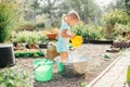 Little blonde girl playing at garden with water in a tin basin. Kids gardening. Summer outdoor water fun. Childhood in the country Royalty Free Stock Photo