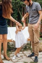 Little blonde girl playing and holding her young parents hand in the garden. Child enjoying with mon and dad. Love and family Royalty Free Stock Photo