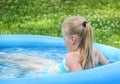 Little blonde girl playing in outdoor swimming pool on hot summer day. Royalty Free Stock Photo