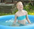 Little blonde girl playing in outdoor swimming pool on hot summer day. Royalty Free Stock Photo