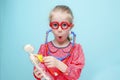 Little blonde girl with red glasses listen heart with stethoscope.