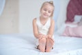 Little blonde girl sitting on the bed