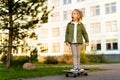 Little blonde girl on a skateboard in the city