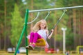 Little blonde girl smiling swinging outdoors on a playgroung