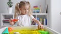 Little blonde girl with two ponytales play with magic sand. Development of fine motor skills, early education, sensorics