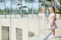 A little blonde girl in a white t-shirt and pink skirt looks over the glass railing at the spectacle Royalty Free Stock Photo