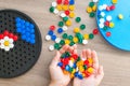 Little blonde girl in a white tshirt playing with plastic multicolor mosaic at home or preschool. Early education