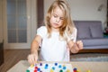 Little blonde girl in a white tshirt playing with plastic multicolor mosaic at home or preschool. Early education concept.