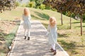 2 little blonde girls with curly hair are walking in a summer park. Cute and little girls on the street. 2 sisters walking outside Royalty Free Stock Photo