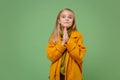 Little blonde kid girl 12-13 years old in yellow coat posing isolated on pastel green background children portrait Royalty Free Stock Photo