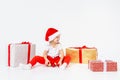 Little blonde kids in Santas hat sitting between gift boxes and playing with christmas balls. Isolated on white background. Royalty Free Stock Photo