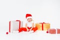 Little blonde kids in Santas hat sitting between gift boxes and playing with christmas balls. Isolated on white background. Royalty Free Stock Photo