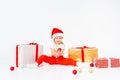 Little blonde kids in Santas hat sitting between gift boxes and playing with christmas balls. Isolated on white Royalty Free Stock Photo