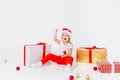 Little blonde kids in Santas hat sitting between gift boxes and playing with christmas balls. Isolated on white Royalty Free Stock Photo