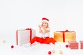 Little blonde kids in Santas hat sitting between gift boxes and playing with christmas balls. Isolated on white Royalty Free Stock Photo