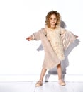 Little blonde model in golden necklace, fluffy pink dress and fur coat, shoes. Spread her hands, smiling, posing isolated on white Royalty Free Stock Photo