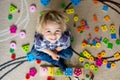 Little blonde toddler child, boy playing with wooden toys developing and learning