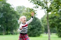 Little blondy girl playing with soap bubbles in summer park